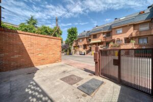 Sunny residential neighborhood with brick houses and green trees on a clear day.